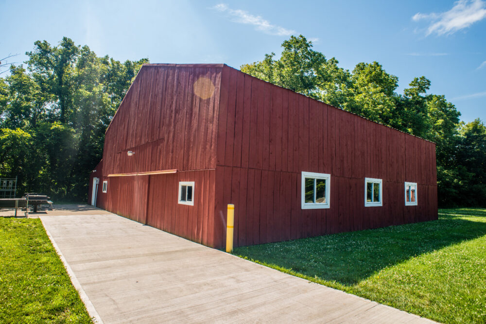 A large barn with a wide concrete walkway leading to a set of sliding doors.