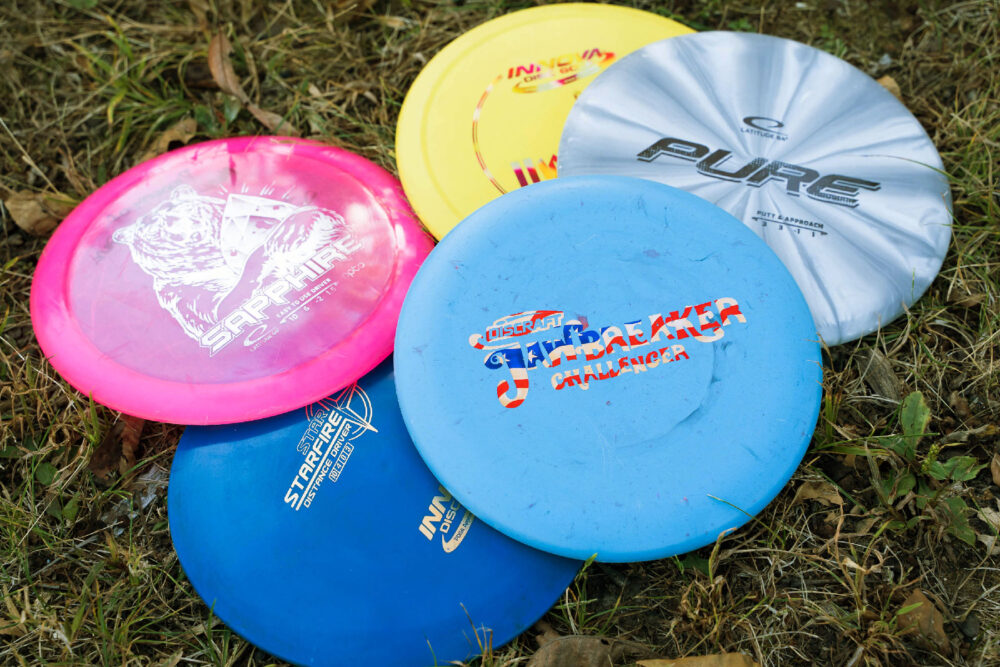 Five discs laying in the grass in a group.