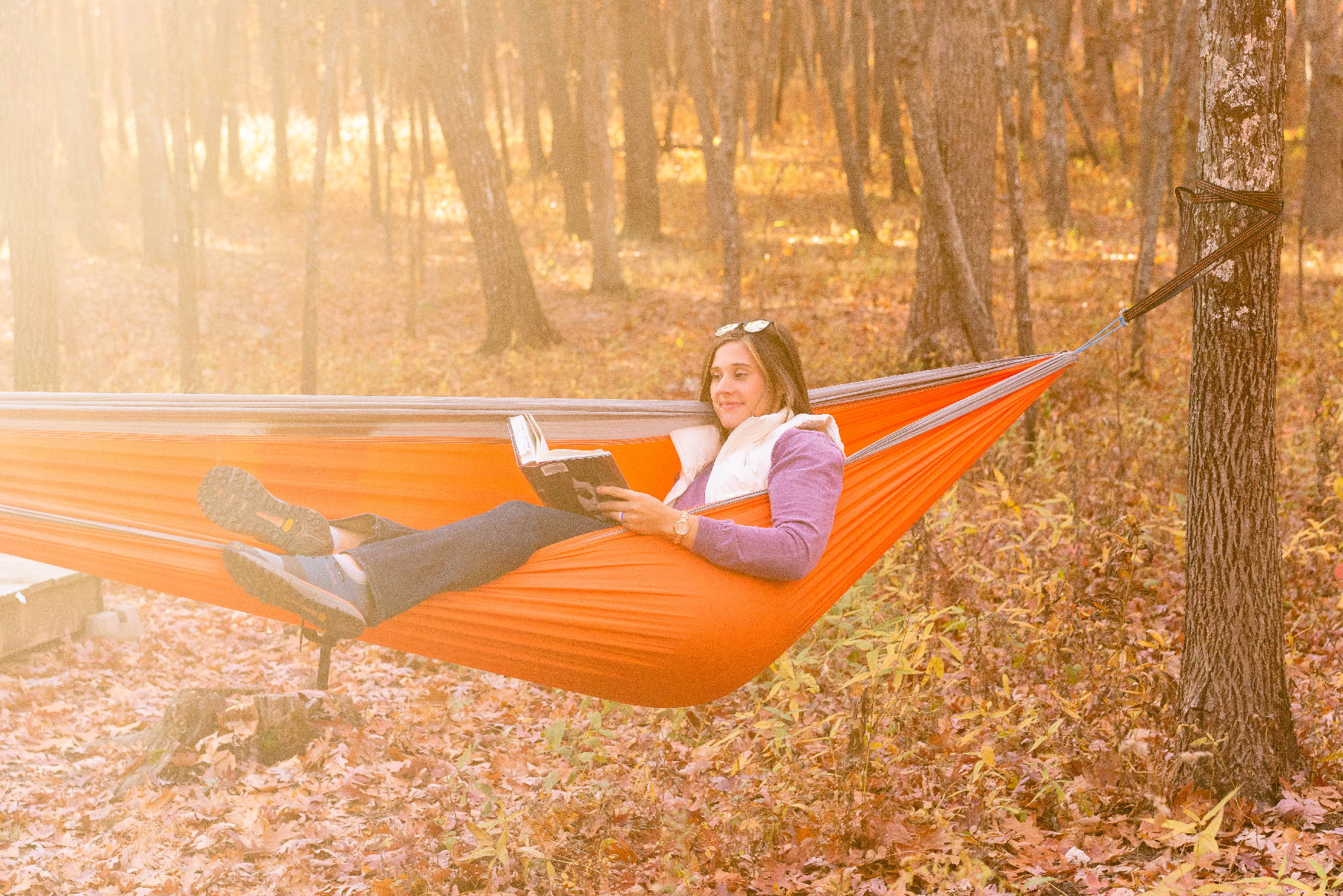 A woman in a hammock reading a book.