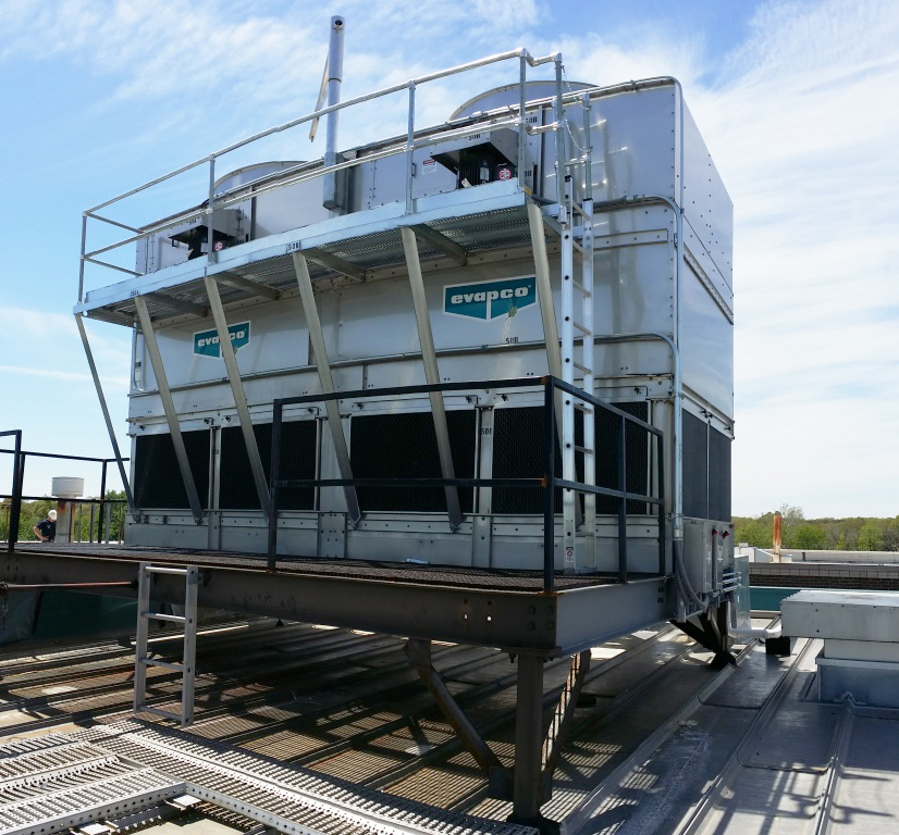 A large metal box with fans on the top - part of an HVAC system. The box has a ladder attached for access by maintenance crew and is on the roof of a building.