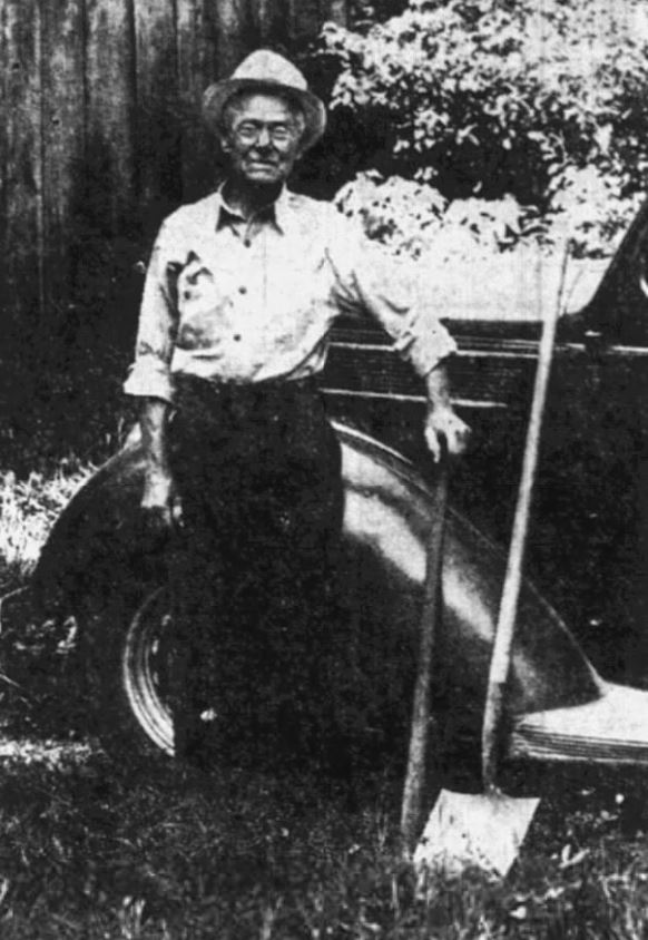 Old Photo of a man standing with a shovel in his hand.