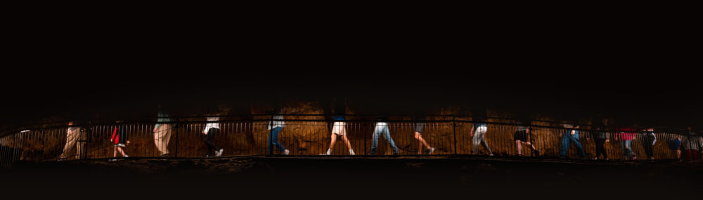 Photo of the bottom half of people as they walk along a path through a cave.