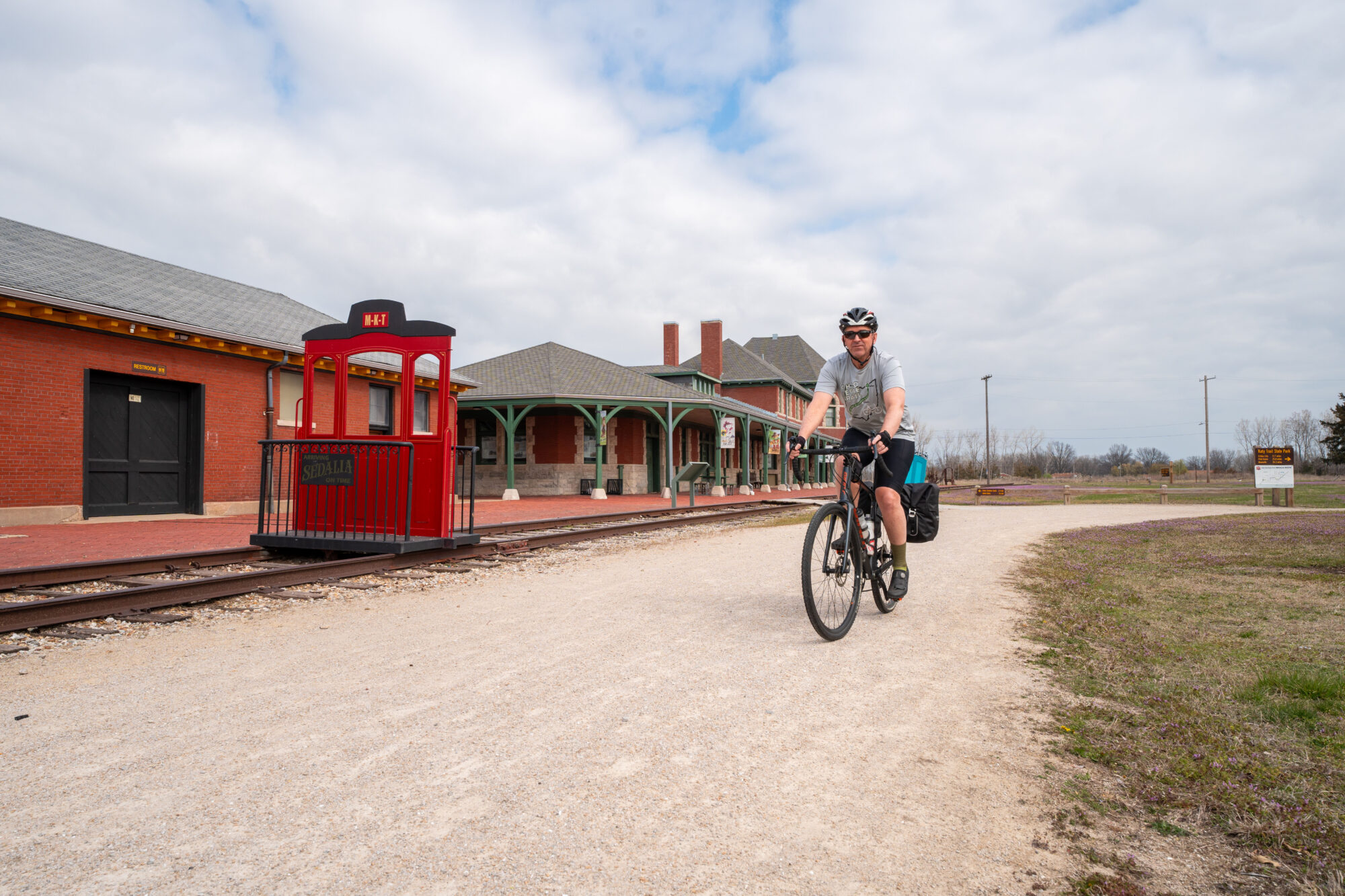 Man on a bike riding along retired railroad and station depot