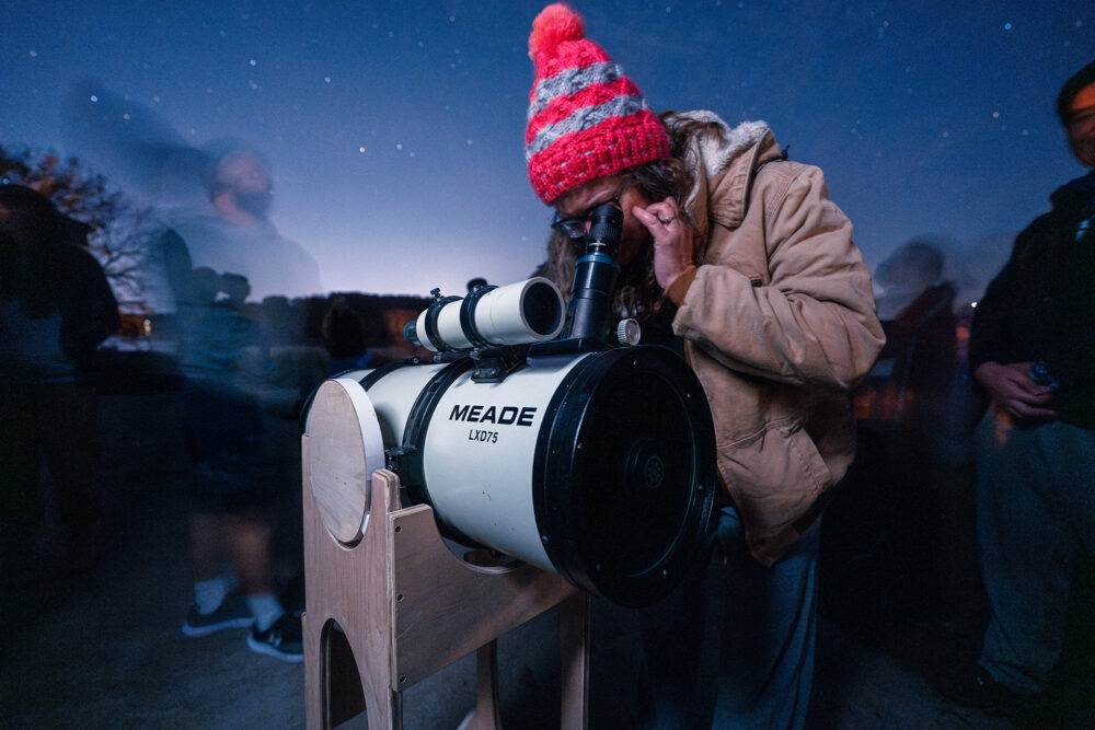 A person looks through the eye piece of a telescope
