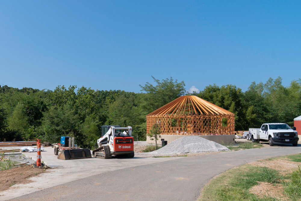 Bob cat and truck sit next to a round structure being made into a Yurt.