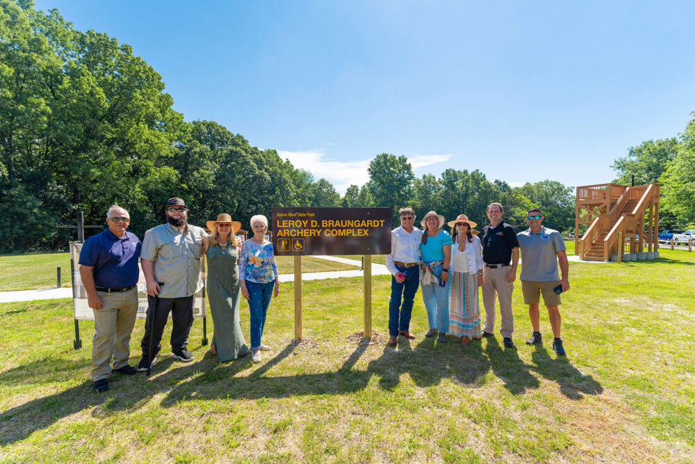 A group of people stand either side of a dedication sign.