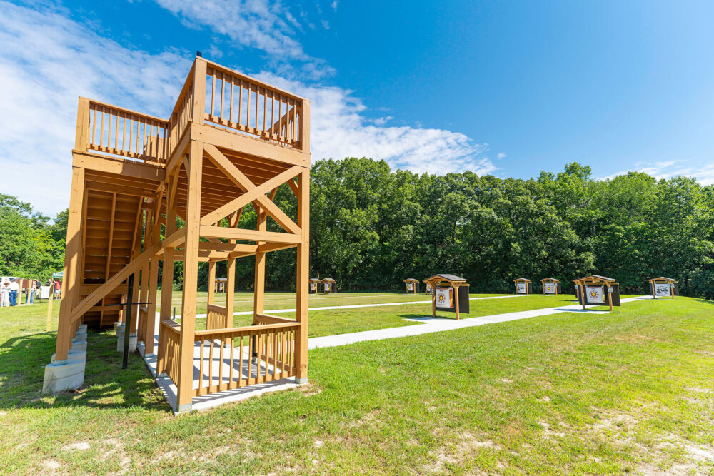 A large wooden structure stands facing an open area with small wooden targets.