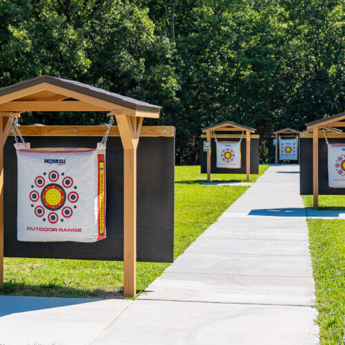 Small wooden structures hold square targets going back incrementally toward a wooded area.