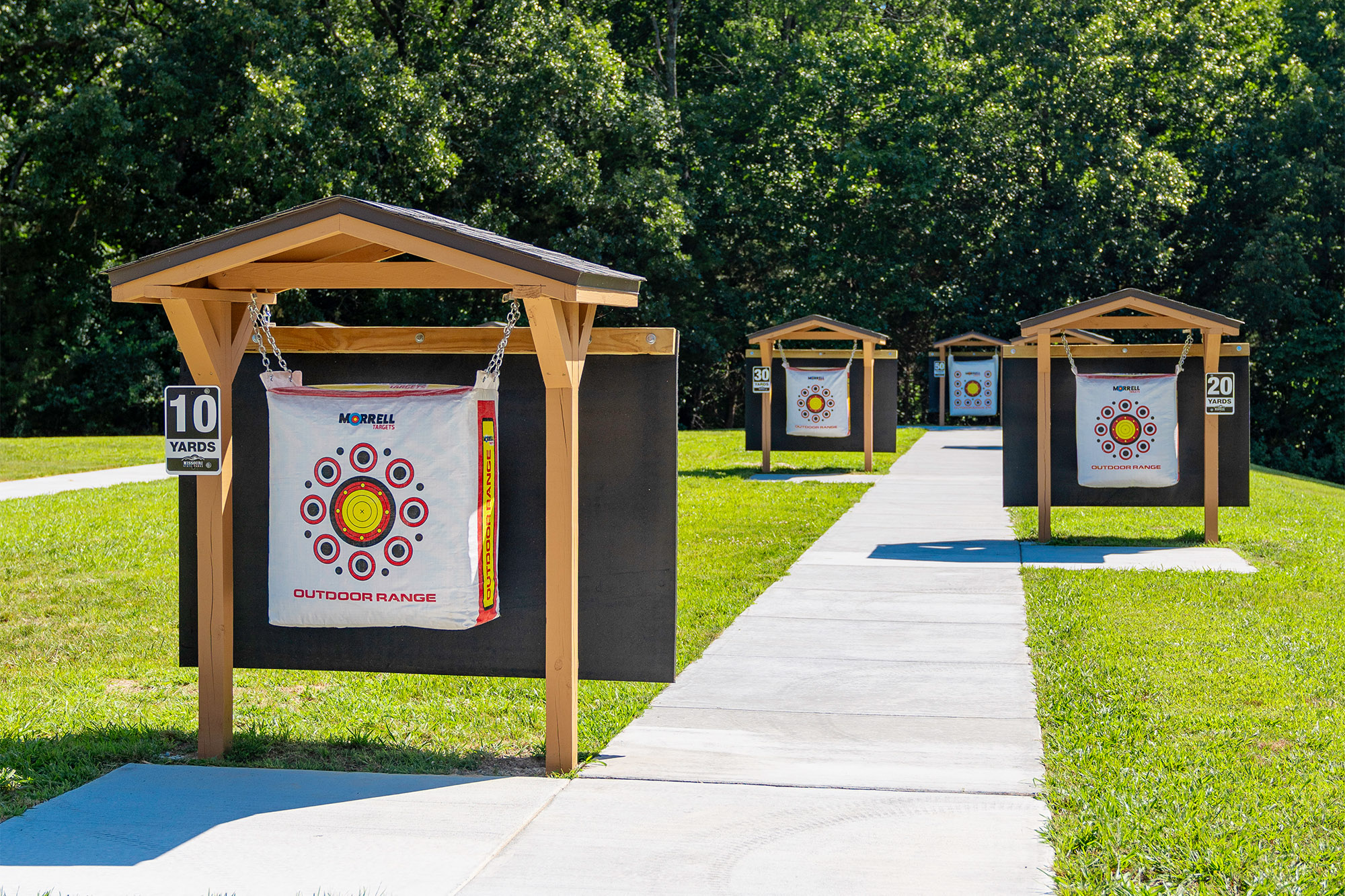 Small wooden structures hold square targets going back incrementally toward a wooded area.