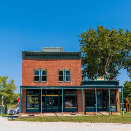 Brick building stands along the side of a gravel trail and a roadway marked "Welcome Center".