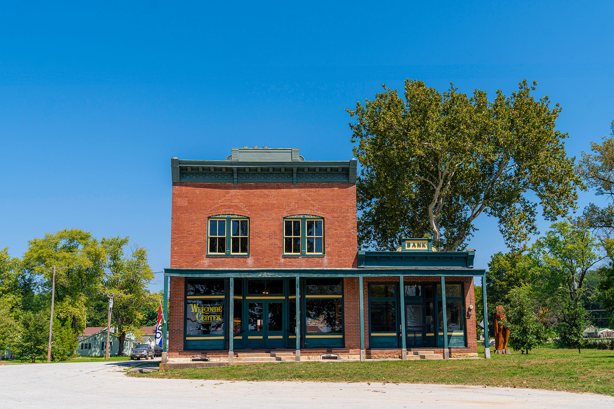 Brick building stands along the side of a gravel trail and a roadway marked "Welcome Center".