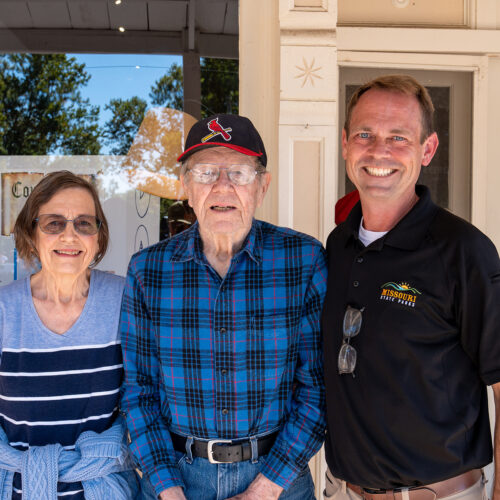 A man in a Missouri State Parks uniform stands next to an elderly man and woman. The elderly people are the parents of the uniformed man.