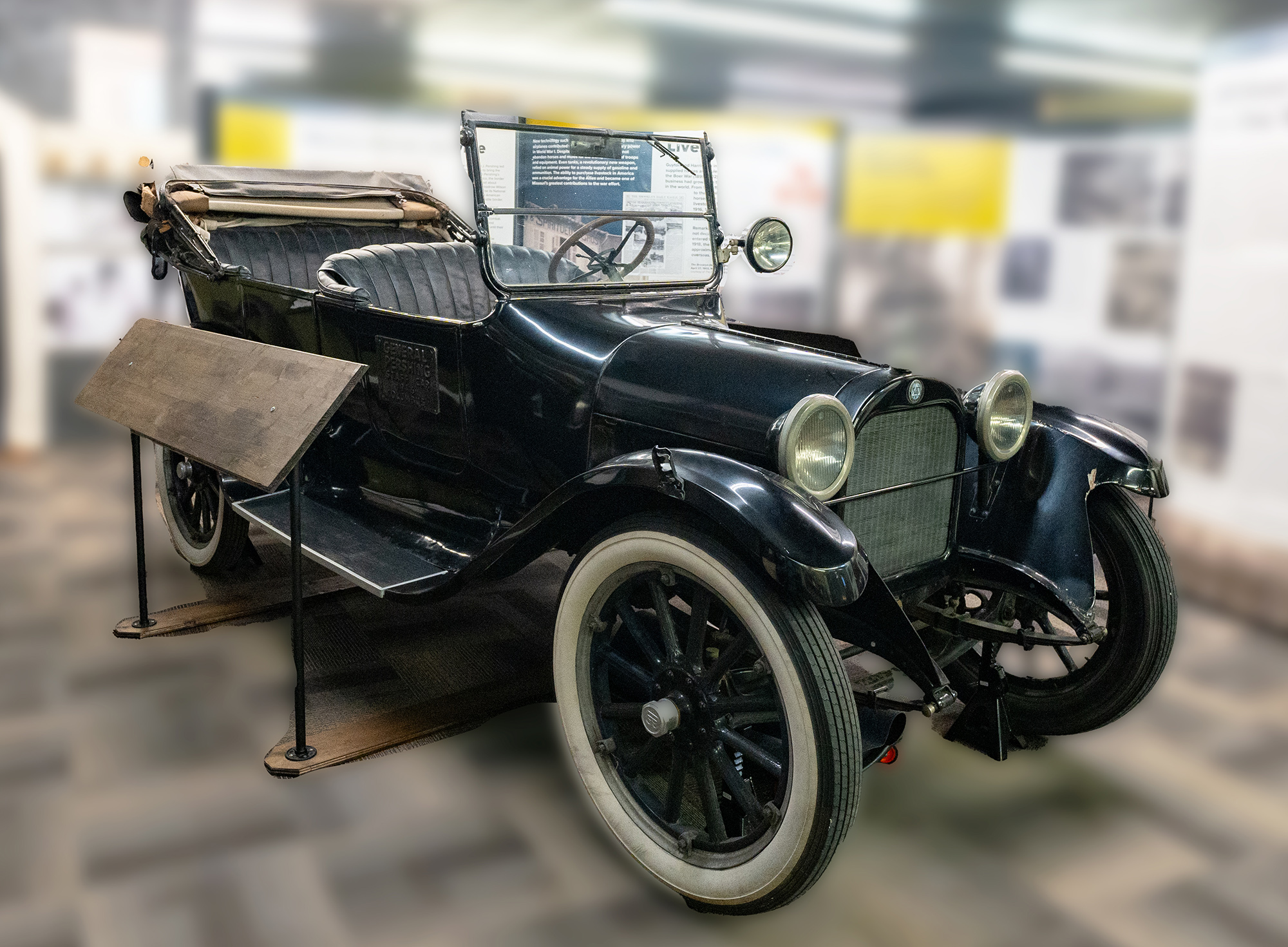 An open air model T car displayed at a museum surrounded by military history at the Perishing historic site.
